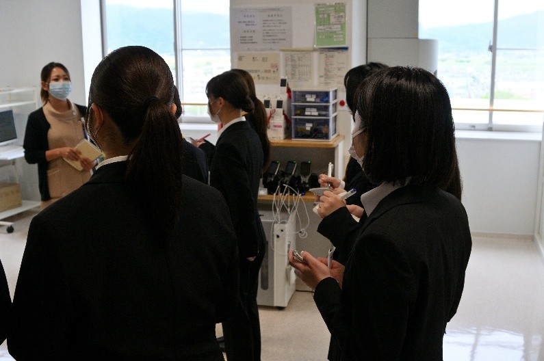 卒業生の先輩から業務内容について説明を受ける学生たち